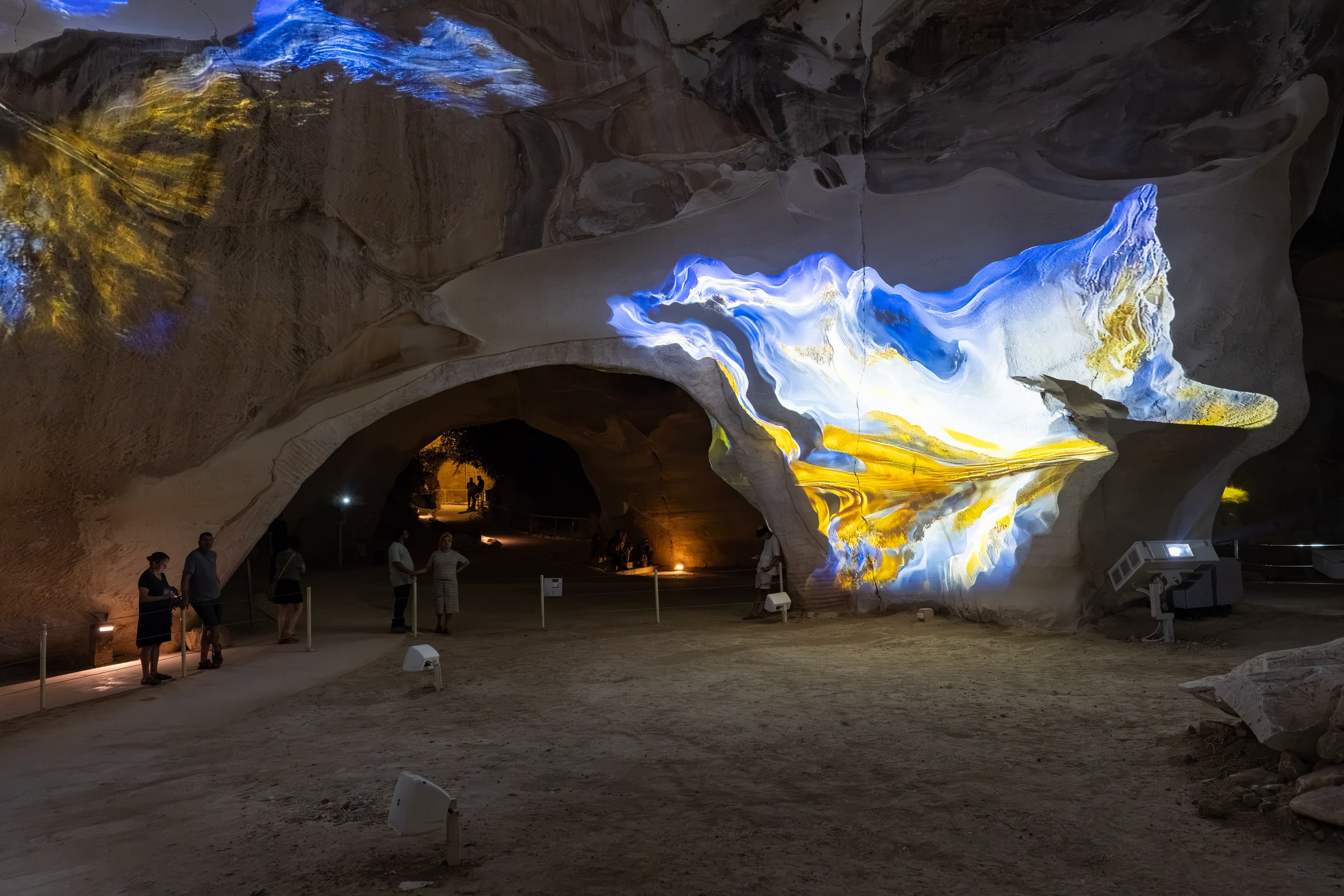 A flowing blue, white and yellow projection stretches across a stone arch.